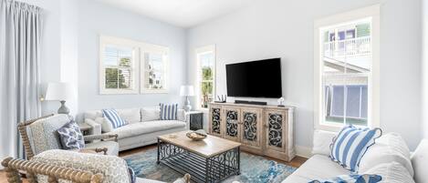 A living room with a sofa, armchair, coffee table, and TV.