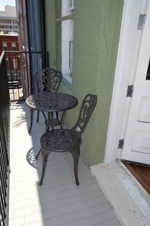 Bistro set on the balcony offers a cozy nook for coffee in the morning or cocktails as you overlook the Picayune Alley - Vintage Advertisements Themed  luxury condo, 2 blocks from French Quarter (New Orleans)