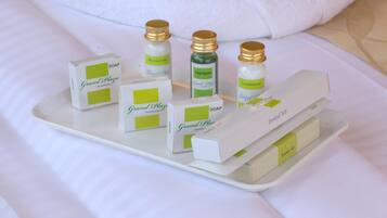 Una bandeja con diversos artículos de tocador del hotel Grand Plaza, incluyendo jabón, champú, acondicionador y un kit de higiene bucal.
