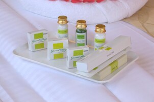 Una bandeja con diversos artículos de tocador del hotel Grand Plaza, incluyendo jabón, champú, acondicionador y un kit de higiene bucal.