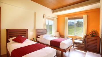 Habitación con dos camas, techo de madera, ventana con cortinas y vista a zonas verdes.
