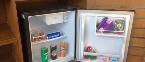 A compact refrigerator with a freezer compartment on top, containing various beverages and snacks.