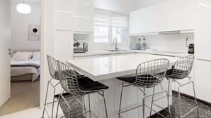Een moderne keuken met witte kasten, een centraal eiland met barkrukken en een zichtbare broodrooster.