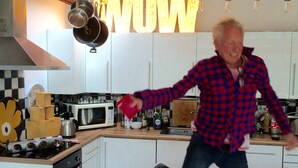 Cuina moderna amb armaris blancs, sostre de fusta i un gran rètol il·luminat que diu 'WOW'.