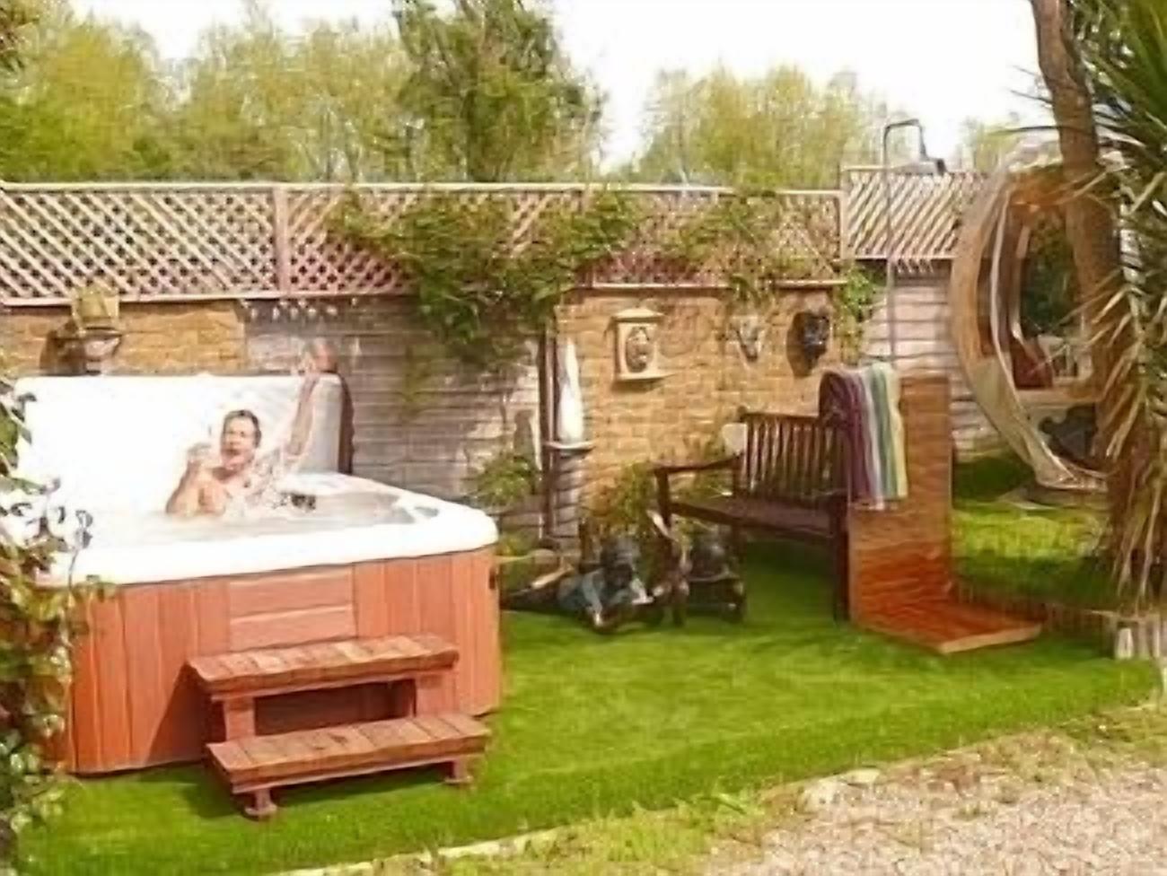 A hot tub in a backyard with a wooden deck and a small wooden structure.