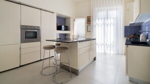 Eine moderne Küche mit einer zentralen Kochinsel, zwei Barhocker, einem Backofen und einer Mikrowelle.