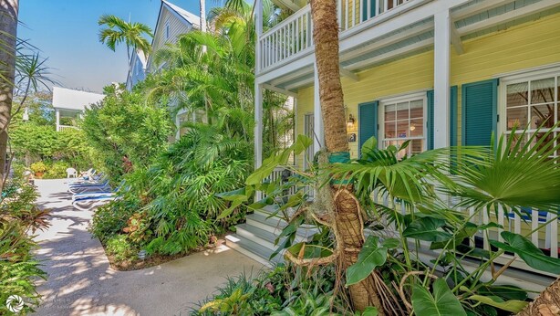 Un edificio de estilo tropical con un porche, rodeado de exuberante vegetación y palmeras.