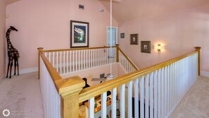 Un escalier avec des rampes blanches et une main courante en bois, menant à l’étage supérieur.