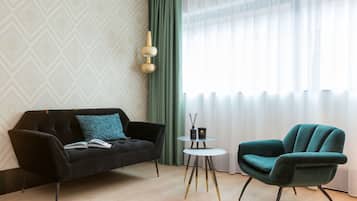 Una sala de estar moderna con un sofá negro, un sillón turquesa y una pequeña mesa redonda con dos velas.