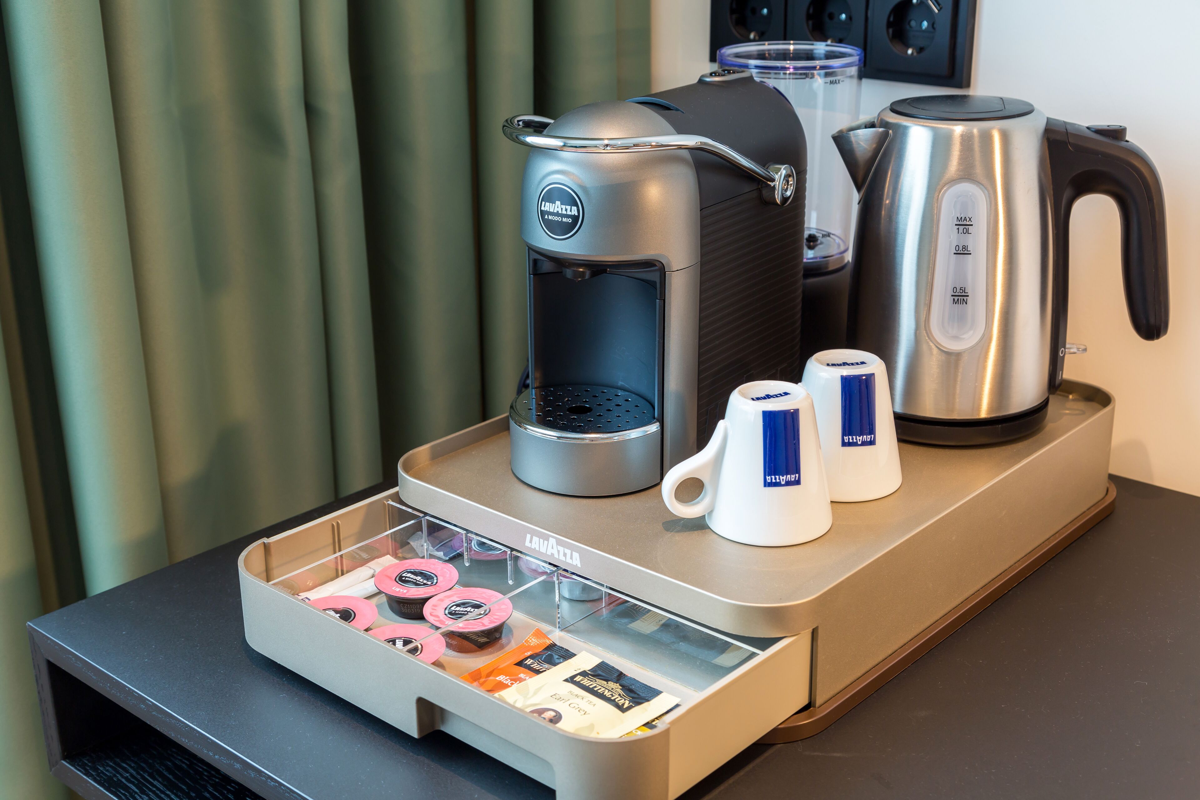 A coffee station with a coffee maker, a kettle, and a coffee pot on a counter.