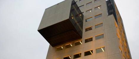 Ein modernes Gebäude mit einem außergewöhnlichen architektonischen Design, das einen vorspringenden Teil und zahlreiche Fenster aufweist.