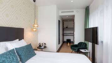 A hotel room with a large bed, a TV, a desk, and a chair.