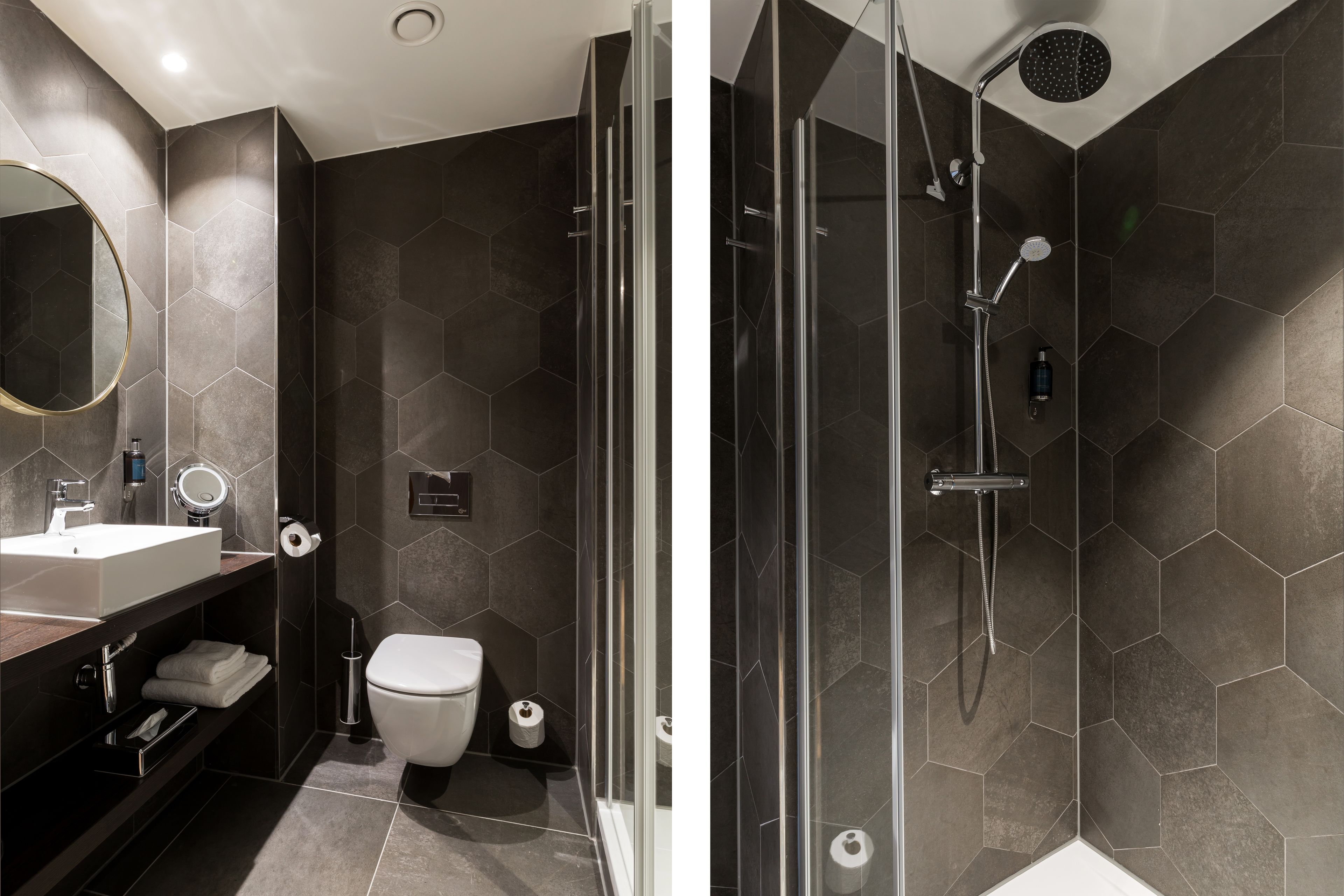 A modern bathroom with a glass-enclosed shower, a large mirror, and a dark hexagonal tile design.