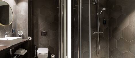 A modern bathroom with a glass-enclosed shower, a large mirror, and a dark hexagonal tile design.