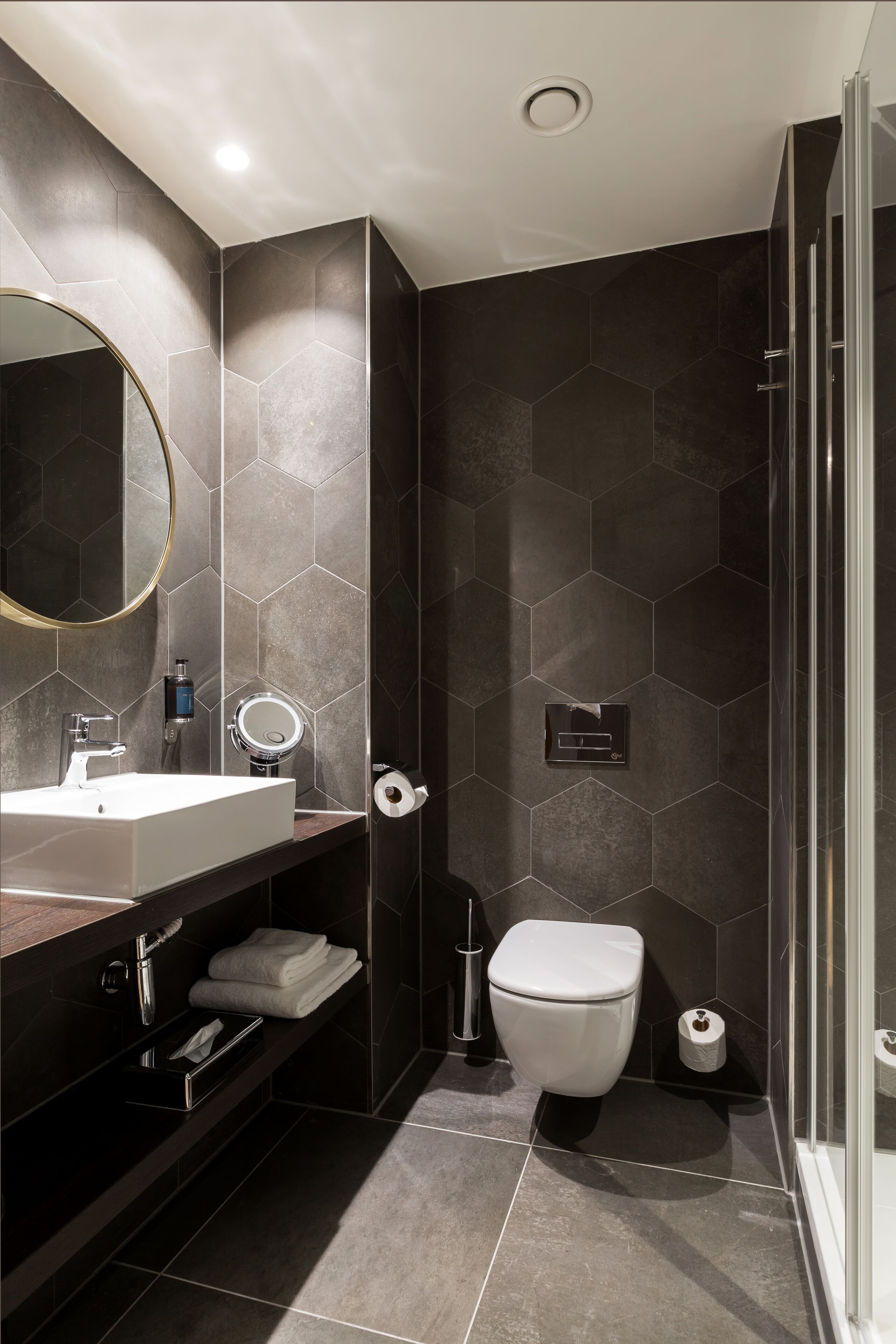 A modern bathroom with a large mirror, a sink, a toilet, and a shower area.
