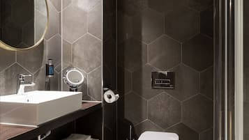 A modern bathroom with a large mirror, a sink, a toilet, and a shower area.