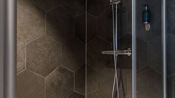 A shower with a rain showerhead, a handheld showerhead, and a handheld shower attachment.