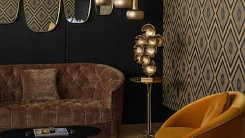 Una sala de estar moderna con un sofá marrón, un sillón amarillo, una mesa de centro redonda y una escultura dorada decorativa.