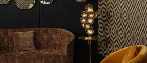 A modern living room with a brown sofa, a yellow armchair, a round coffee table, and a decorative gold sculpture.