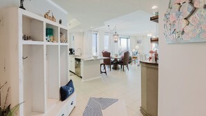 A spacious kitchen with white cabinetry, a dining area with a round table and chairs, and a large decorative fish mural on the wall. - 501W - Contemporary 3BR Beachfront Condo! (Orange Beach)
