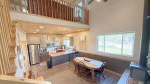 A spacious kitchen with a large island, wooden ceiling, and a dining area with a view of the outdoors. - The Cedars Country Cottage (Blanding)