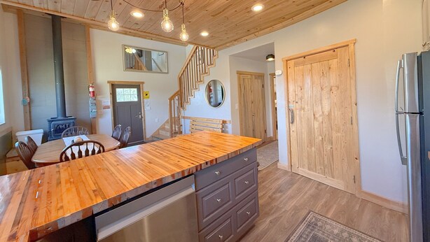 A kitchen with wooden ceiling, a central island, a refrigerator, and a stove. - The Cedars Country Cottage (Blanding)