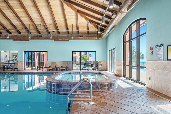 A swimming pool with a hot tub, lounge chairs, and a view of the outdoors.
