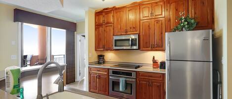 A modern kitchen with wooden cabinets, stainless steel appliances, and a large window.