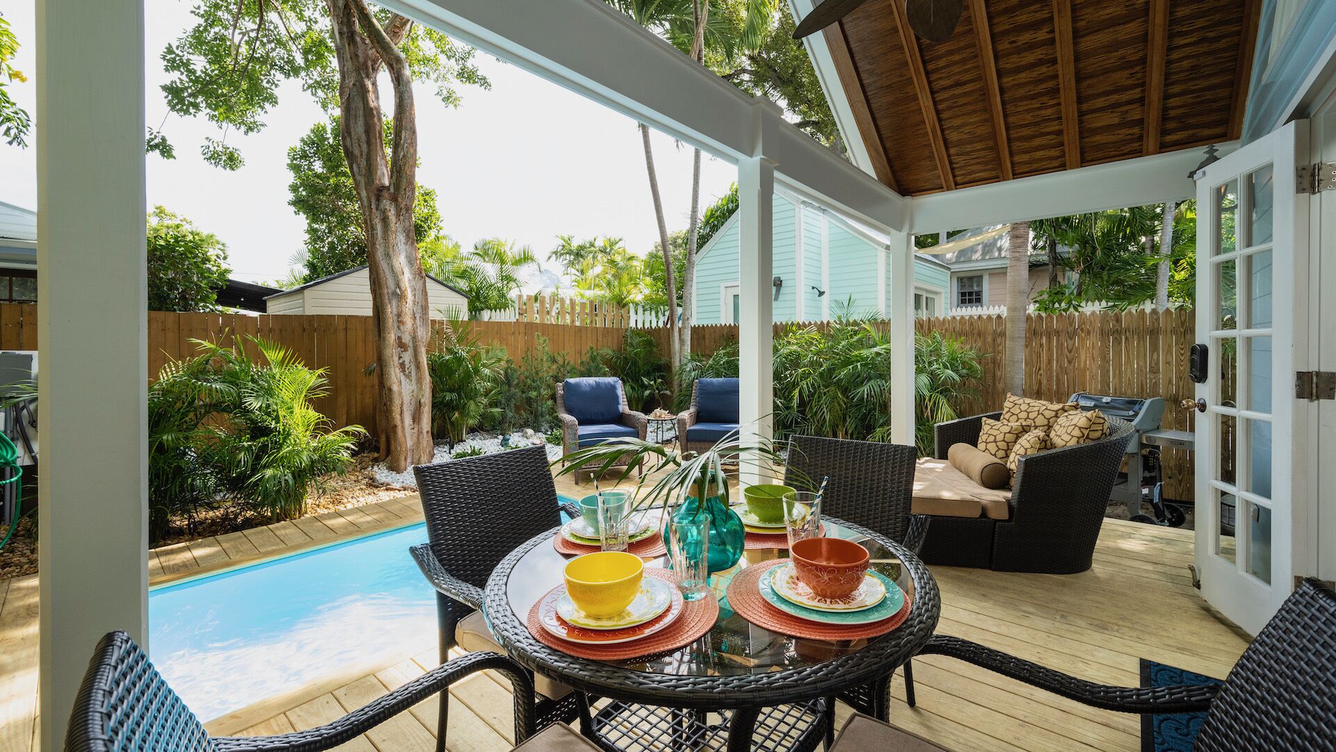 A covered patio with a pool, outdoor furniture, and a wooden deck.