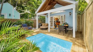 Área da piscina com deck de madeira, mobiliário externo e vista para a casa.