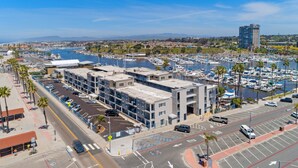 Una marina con barcos, un estacionamiento y un edificio moderno de varios pisos.
