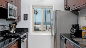 Una cocina compacta con vista a la playa, un refrigerador, una estufa y una cafetera.