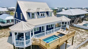 A large house with a pool, multiple decks, and a view of the beach.