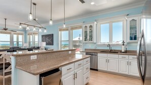 A modern kitchen with white cabinets, granite countertops, and stainless steel appliances.