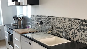 Una cucina moderna con un piano di lavoro nero, mobili bianchi e piastrelle decorate a contrasto.