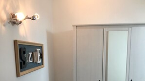 Una stanza con un armadio bianco, una decorazione artistica in cornice al muro e un lampadario.