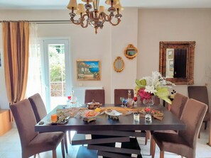 Un coin repas avec une table dressée pour quatre personnes, entourée de chaises, d’un lustre et d’œuvres d’art encadrées accrochées aux murs.