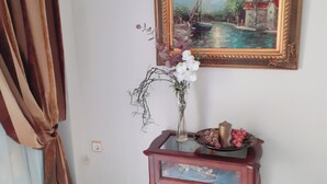 A room with a painting, a vase with flowers, and a small table with a bowl.