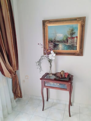 A room with a painting, a vase with flowers, and a small table with a bowl.