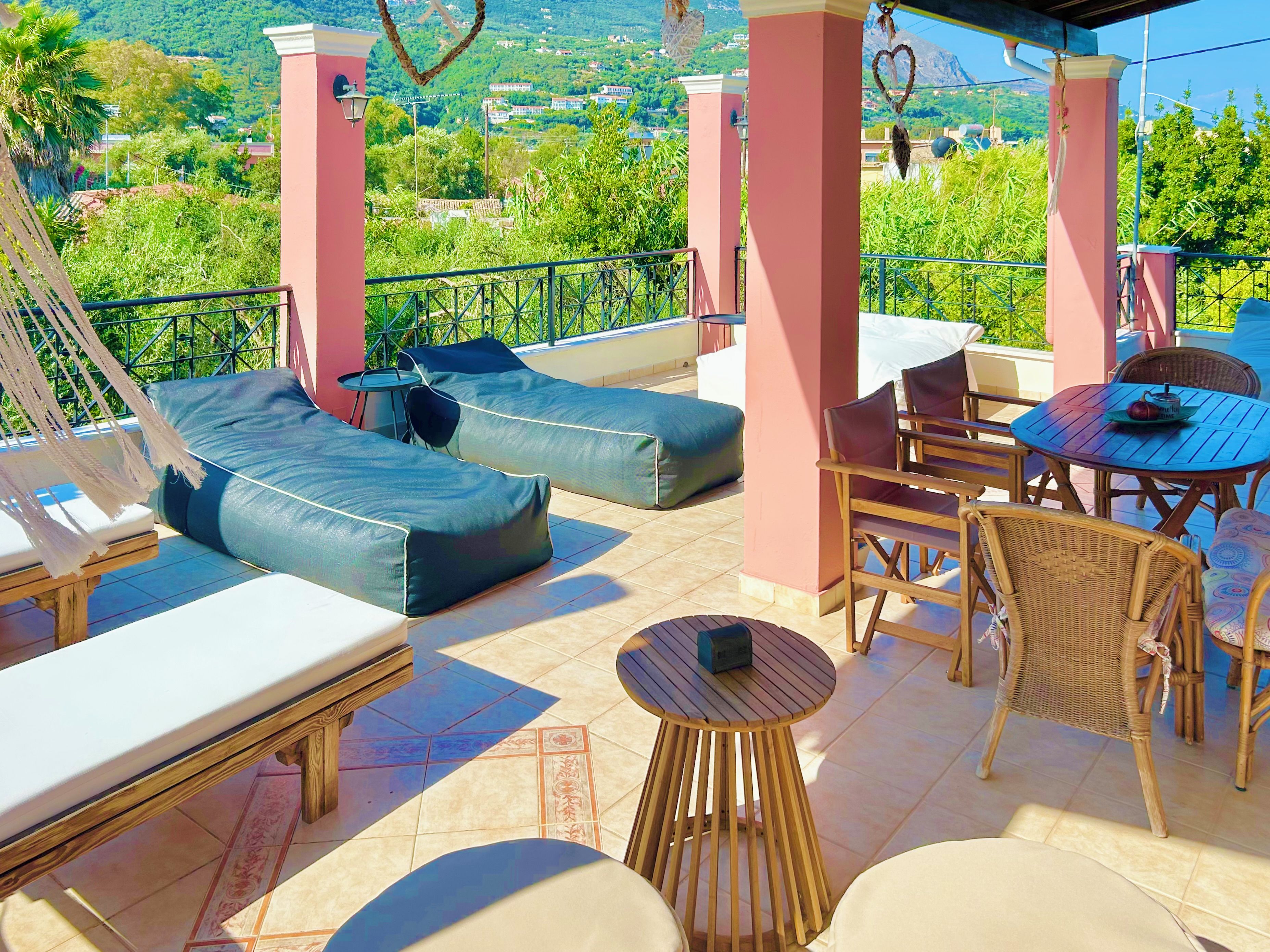 A terrace with a sofa, chairs, and a table, overlooking a scenic landscape.