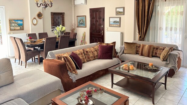 A living room with a sofa, armchairs, a coffee table, and a dining area with a table and chairs.