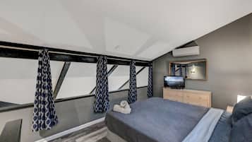 A bedroom with a bed, a dresser, a mirror, and patterned curtains.