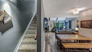 Un intérieur moderne comprenant un escalier, un coin repas et un salon avec une cheminée.