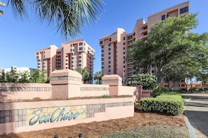 A multi-story hotel with a prominent sign reading "Seachase" and a landscaped area with trees and shrubs.