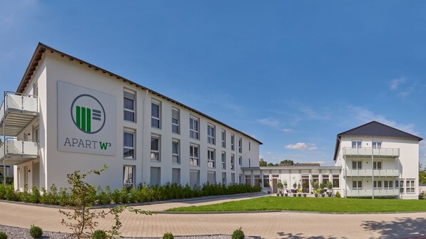 Un bâtiment moderne avec une enseigne indiquant « APARTW3 » et un balcon doté de sièges pour l’extérieur.