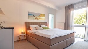 Un dormitorio con cama, mesita de noche, lámpara y un cuadro en la pared.