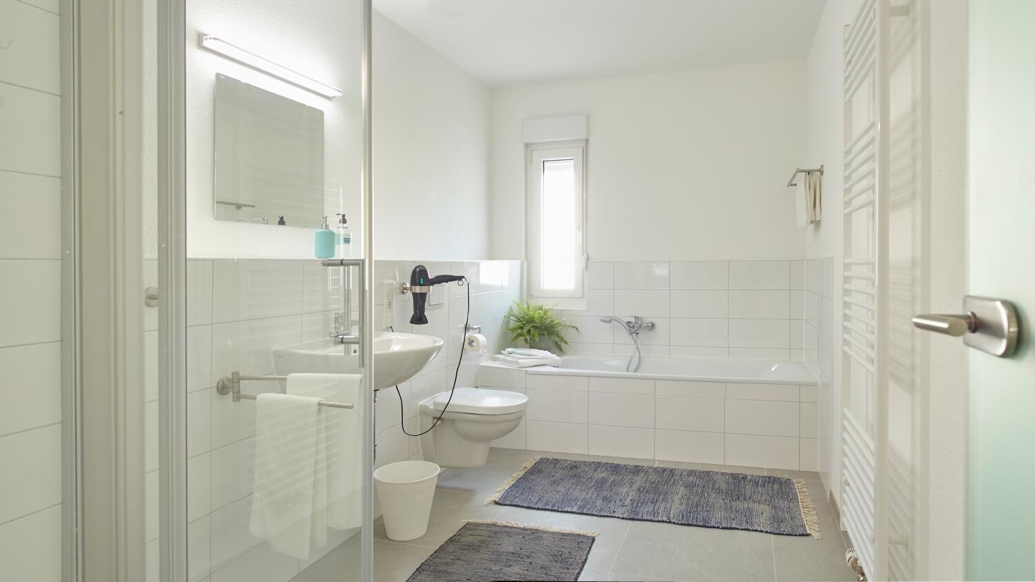 A modern bathroom with a glass shower enclosure, a sink, a toilet, and a bathtub.