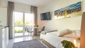 Une chambre d’hôtel avec un lit, un bureau, une chaise, une télévision et une grande fenêtre.