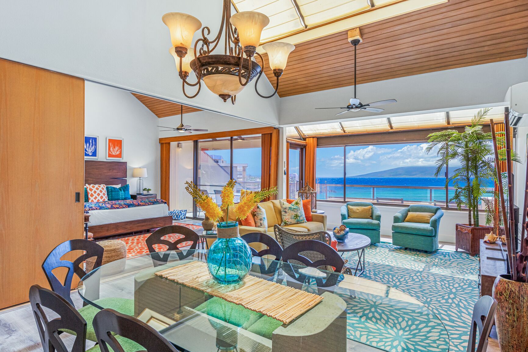 A spacious living area with a large window overlooking the ocean, a dining area with a glass table, and a cozy seating arrangement.