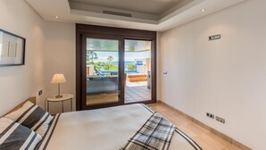 Et hotelværelse med en seng, et natbord, en lampe, en skydedør til en balkon og havudsigt.